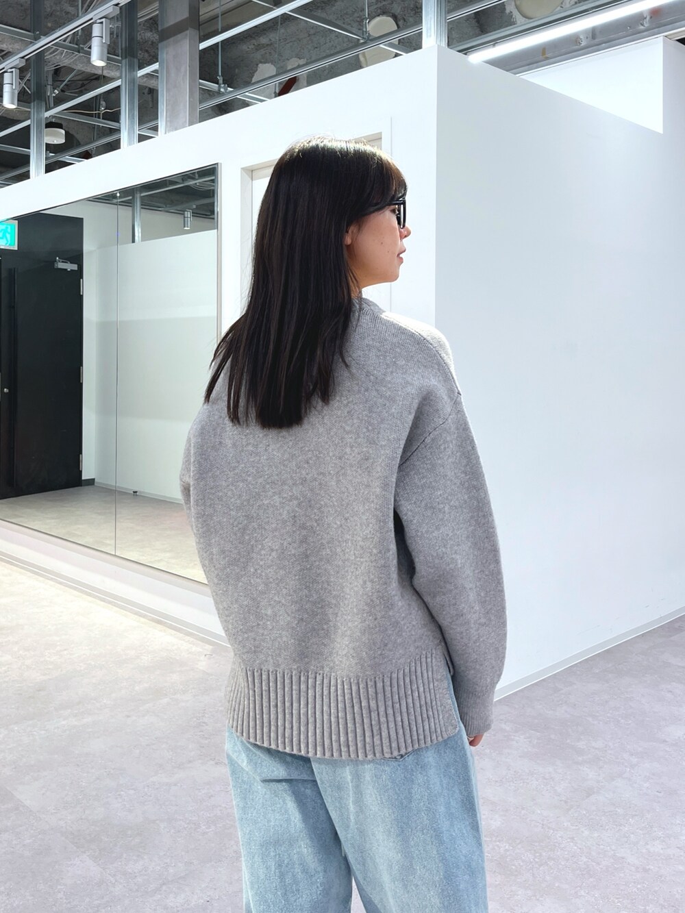 グレー系のニット/セーター、ブルー系のデニムパンツ、ホワイト系のスニーカーを着用したレディースの冬コーディネートの3枚目の写真