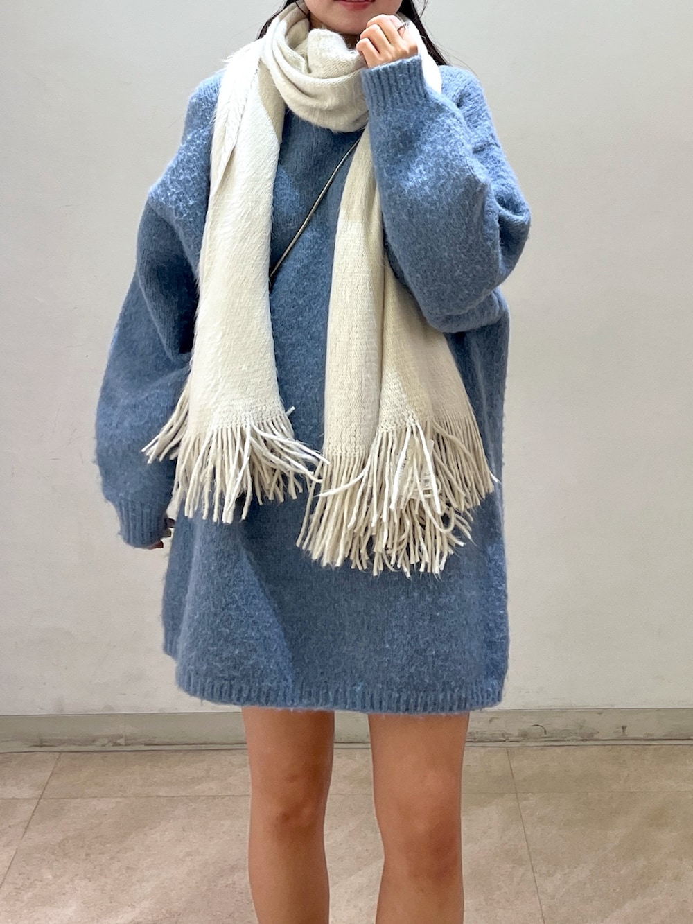 ブルー系のワンピース、シルバー系のハンドバッグ、ブラック系のブーツを着用したレディースの冬コーディネートの5枚目の写真