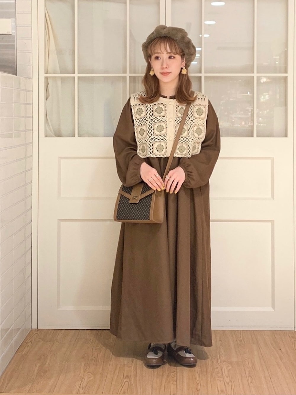 ブラウン系のワンピース、ホワイト系のベスト、ブラウン系のショルダーバッグを着用したレディースの秋コーディネートの2枚目の写真