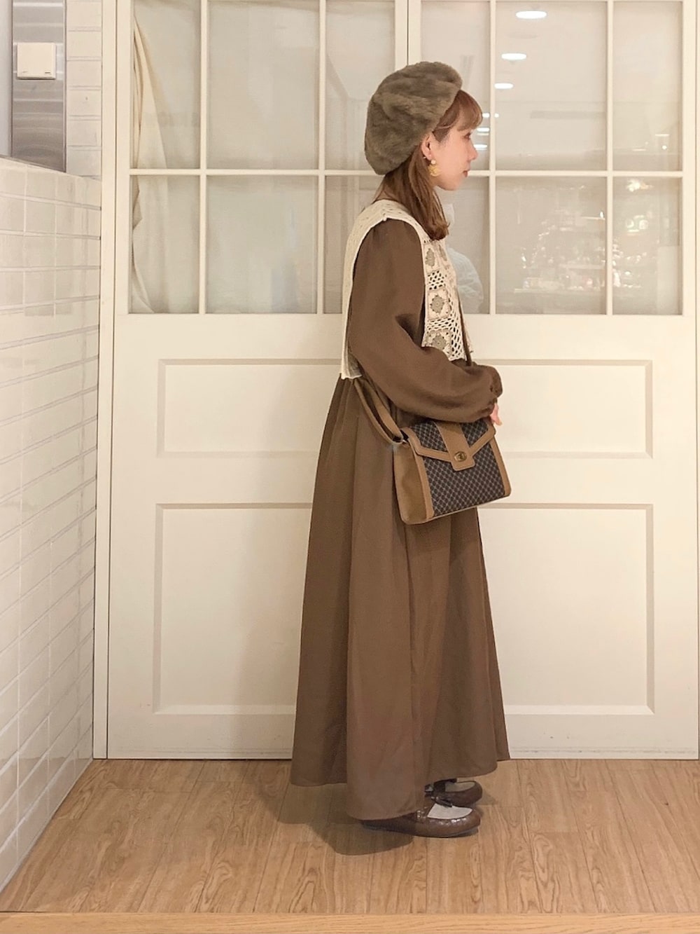 ブラウン系のワンピース、ホワイト系のベスト、ブラウン系のショルダーバッグを着用したレディースの秋コーディネートの3枚目の写真
