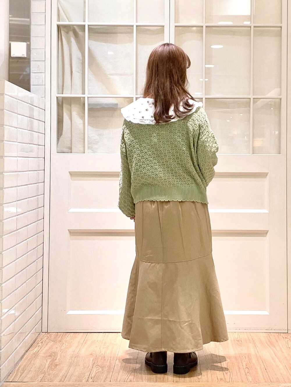 ベージュ系のジャンパースカート、ホワイト系のシャツ/ブラウス、グリーン系のカーディガン/ボレロを着用したレディースの春コーディネートの3枚目の写真