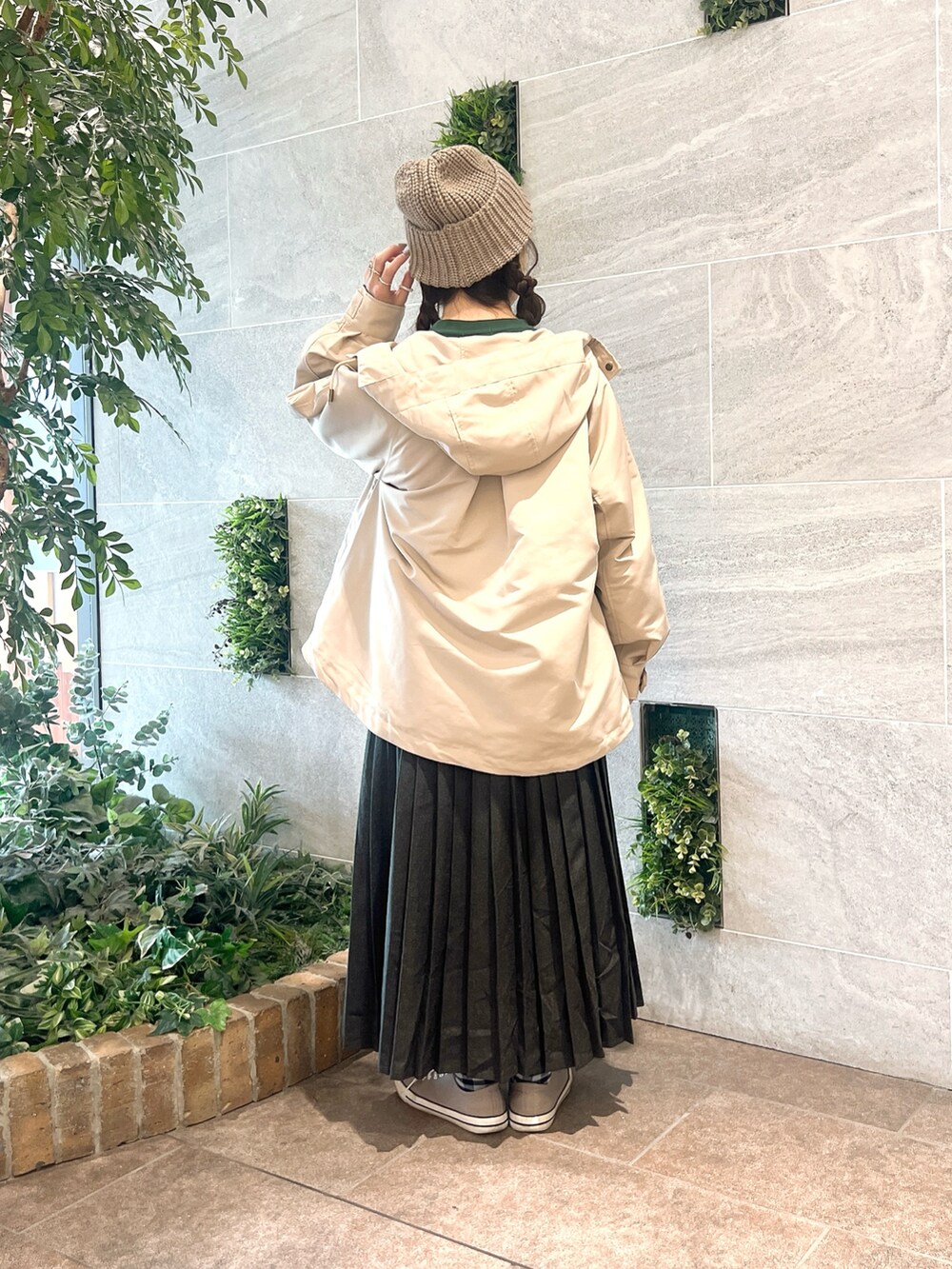 グレー系のスカート、グリーン系のTシャツ/カットソー、ブラウン系のハットを着用したレディースの冬コーディネートの2枚目の写真