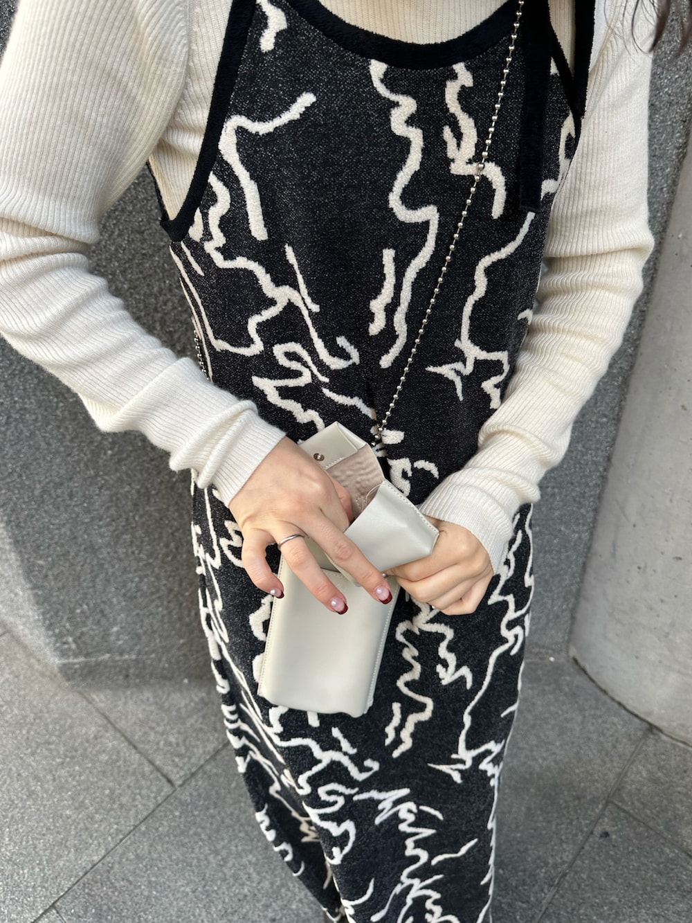 ブラック系のワンピース、ブラック系のブーツ、ホワイト系のスマホケース/カバーを着用したレディースの冬コーディネートの3枚目の写真