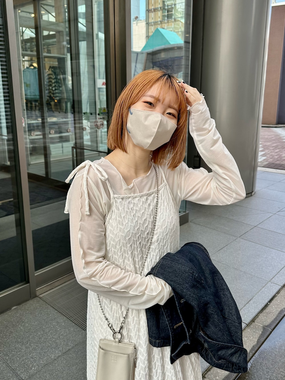 ホワイト系のワンピース、ブラック系のスニーカー、ブルー系のデニムジャケットを着用したレディースの春コーディネートの4枚目の写真