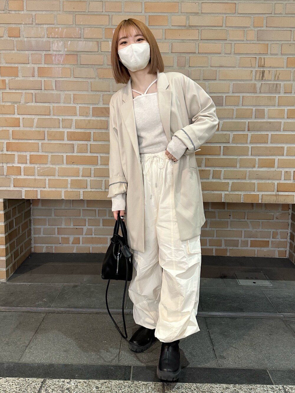 ホワイト系のカーゴパンツ、ブラック系のブーツ、ホワイト系のニット/セーターを着用したレディースの春コーディネートの5枚目の写真