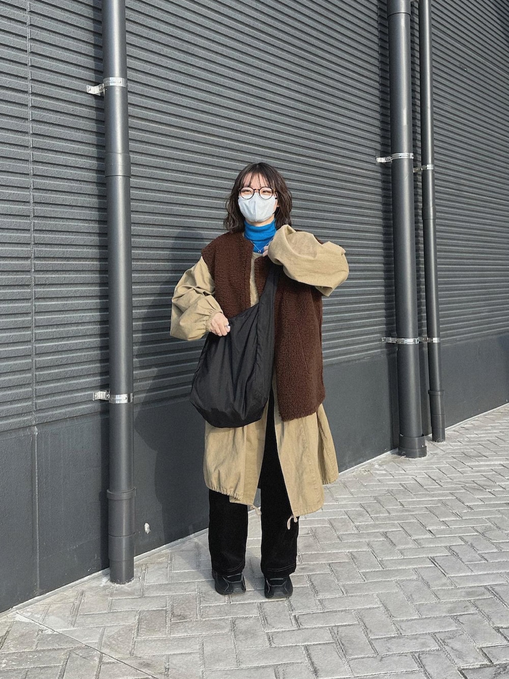 ブラック系のスニーカー、ベージュ系のミリタリージャケット、ホワイト系のベストを着用したレディースの冬コーディネートの2枚目の写真