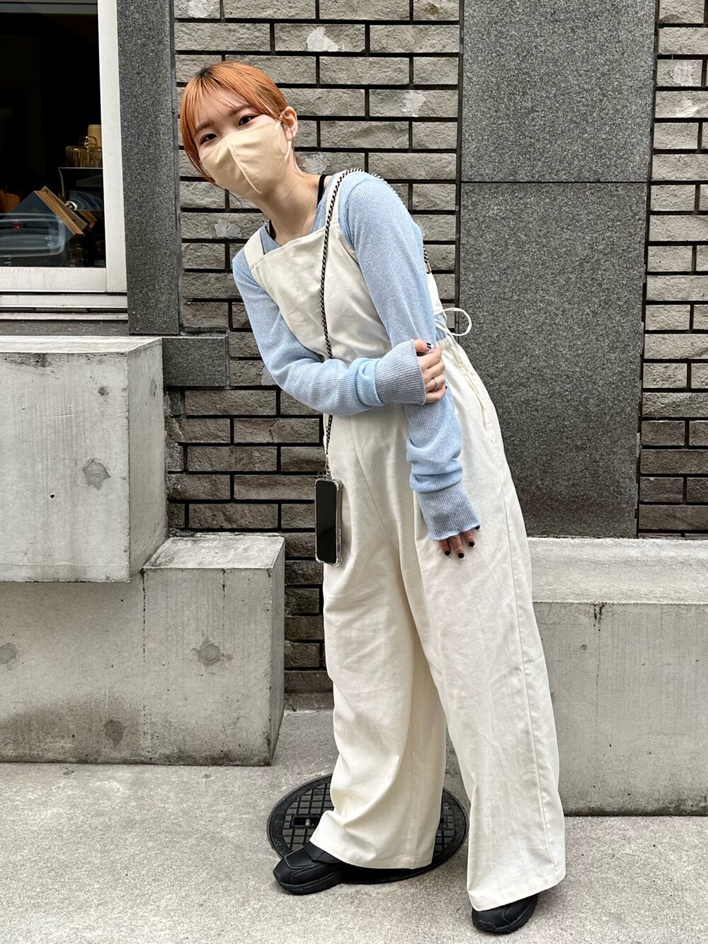ブラック系のスニーカー、ホワイト系のサロペット/オーバーオール、ブルー系のTシャツ/カットソーを着用したレディースの春コーディネートの2枚目の写真