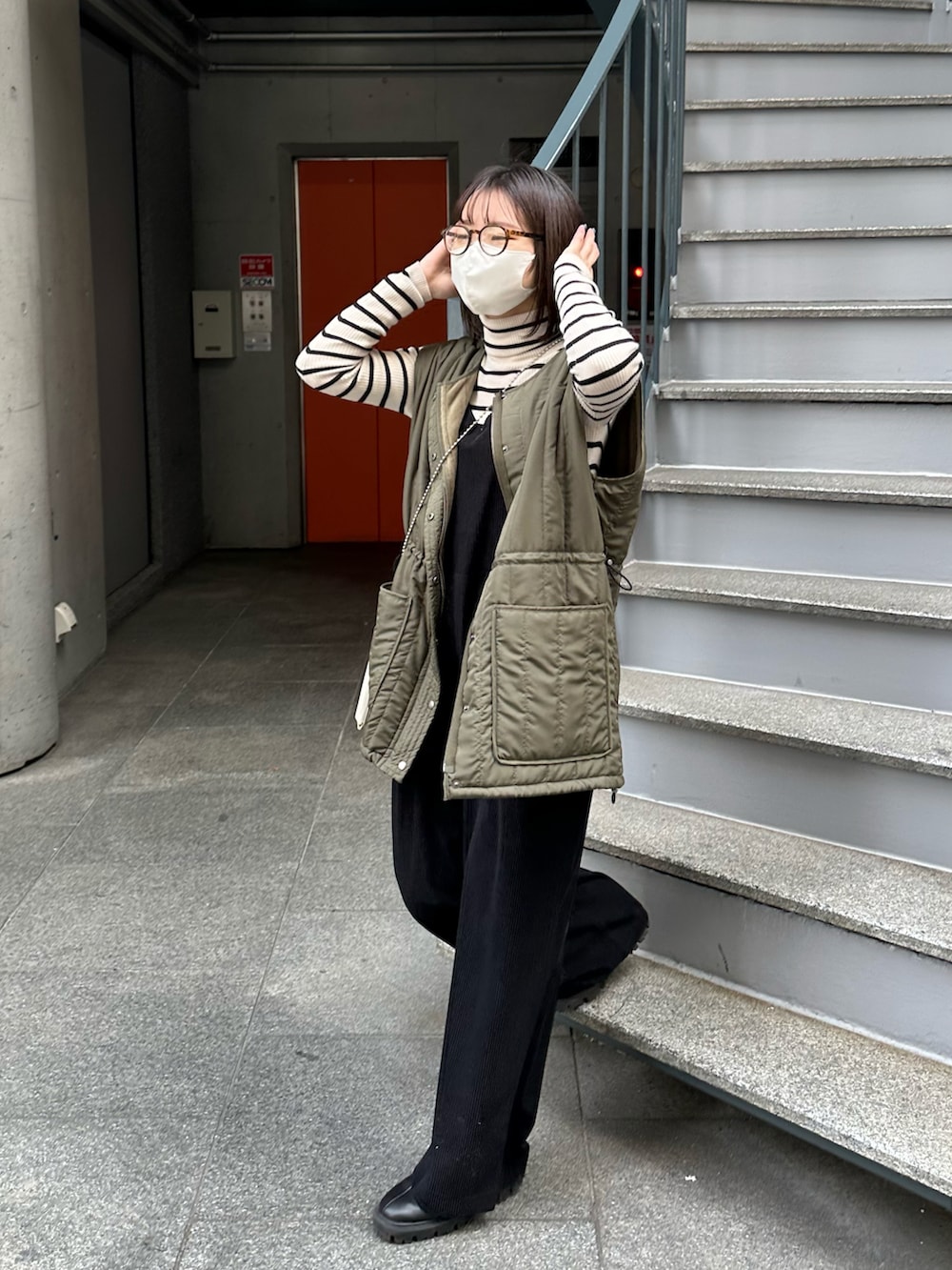 グリーン系のベスト、ブラック系のサロペット/オーバーオール、ブラック系のブーツを着用したレディースの冬コーディネートの4枚目の写真