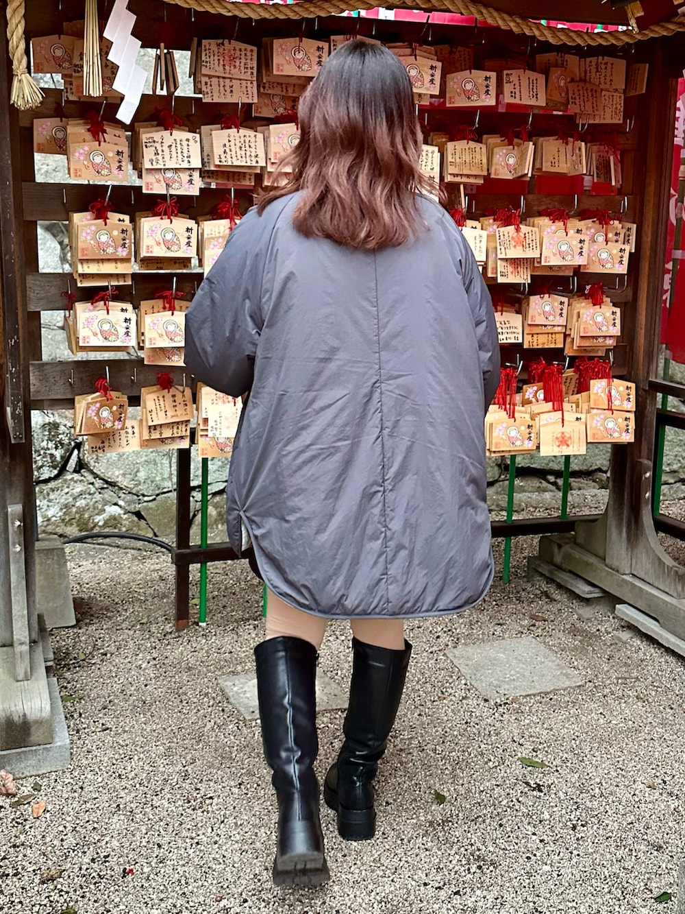 グレー系のワンピース、レッド系のニット/セーター、ブラック系のブーツを着用したレディースの冬コーディネートの2枚目の写真