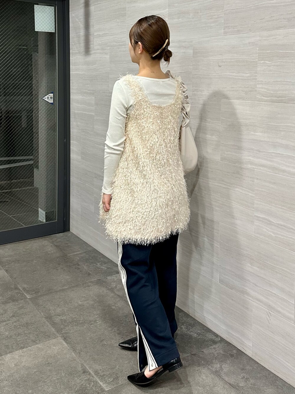 ホワイト系のベスト、ブルー系のスウェットパンツ、ブラック系のパンプスを着用したレディースの春コーディネートの2枚目の写真