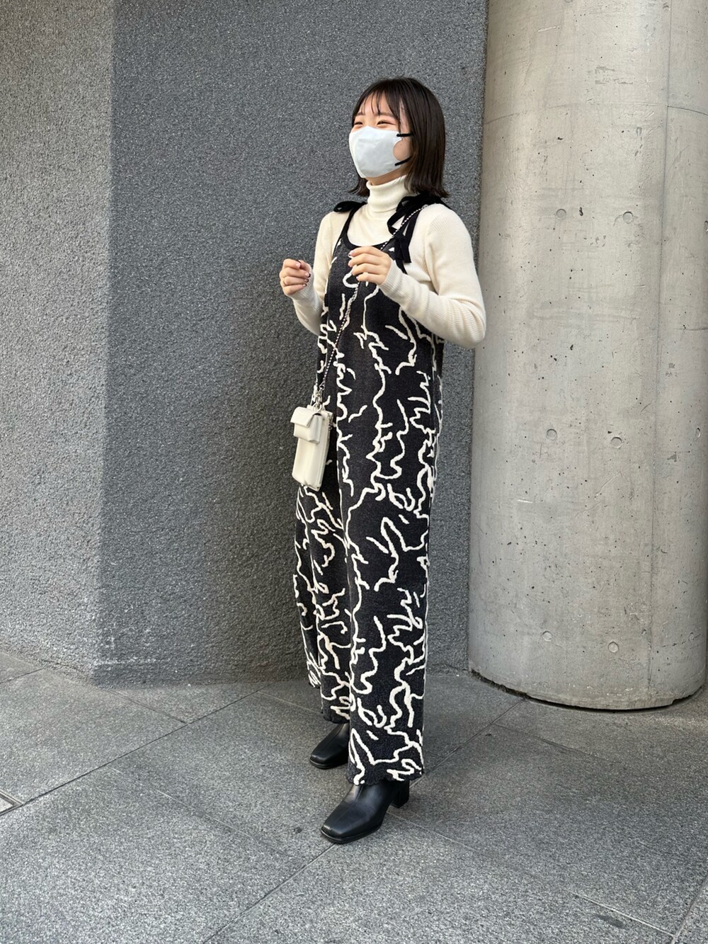 ブラック系のワンピース、ブラック系のブーツ、ホワイト系のスマホケース/カバーを着用したレディースの冬コーディネートの2枚目の写真