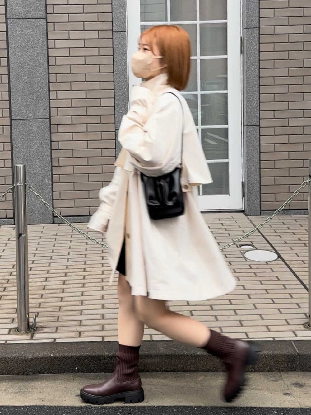 ホワイト系のトレンチコート、ホワイト系のTシャツ/カットソー、ブラック系のスカートを着用したレディースの冬コーディネートの4枚目の写真