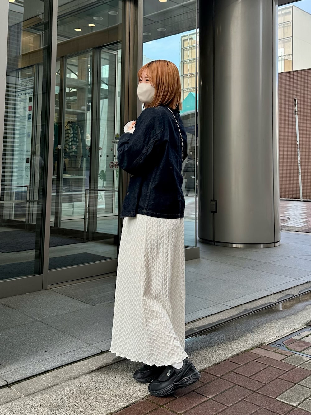 ホワイト系のワンピース、ブラック系のスニーカー、ブルー系のデニムジャケットを着用したレディースの春コーディネートの2枚目の写真