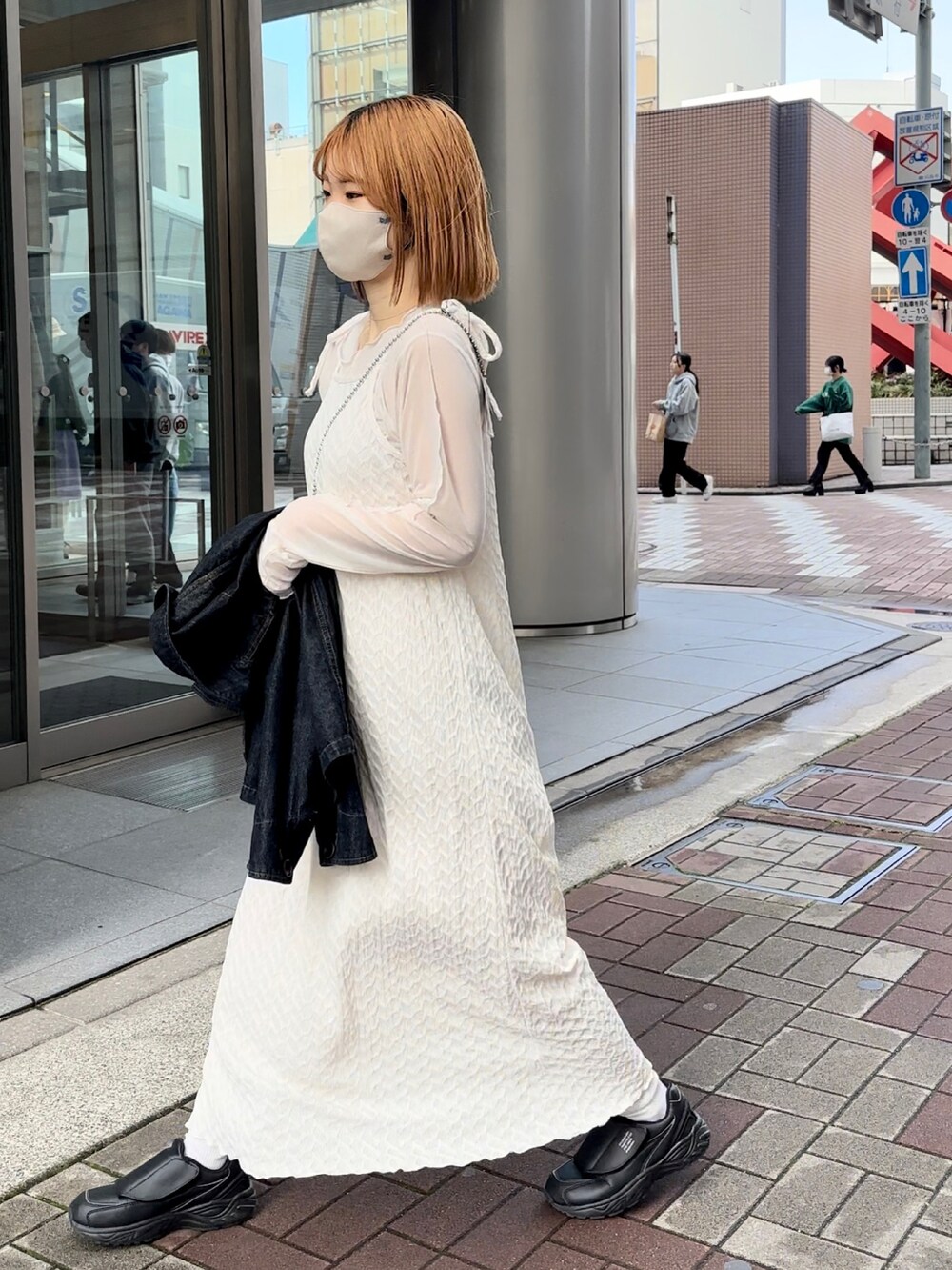 ホワイト系のワンピース、ブラック系のスニーカー、ブルー系のデニムジャケットを着用したレディースの春コーディネートの5枚目の写真