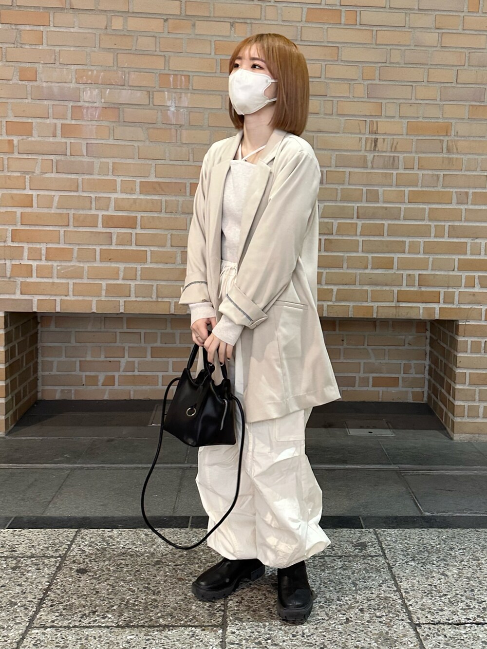 ホワイト系のカーゴパンツ、ブラック系のブーツ、ホワイト系のニット/セーターを着用したレディースの春コーディネートの4枚目の写真