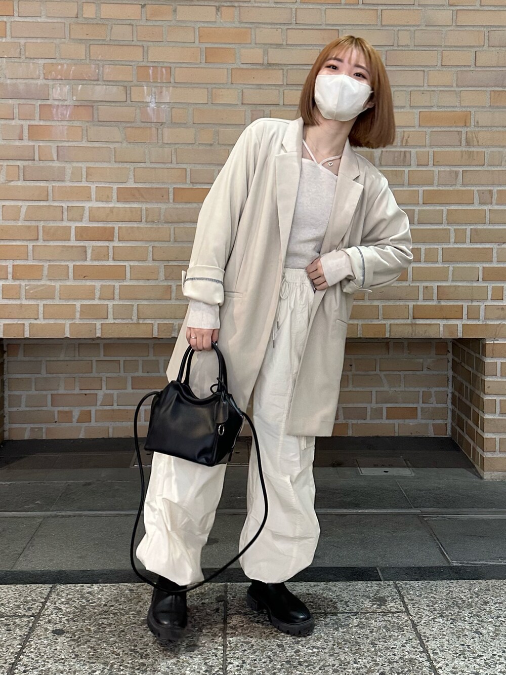 ホワイト系のカーゴパンツ、ブラック系のブーツ、ホワイト系のニット/セーターを着用したレディースの春コーディネートの2枚目の写真