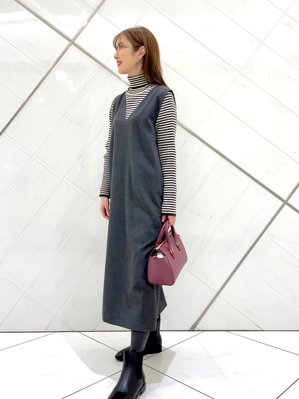 グレー系のステンカラーコート、ホワイト系のニット/セーター、グレー系のワンピースを着用したレディースの冬コーディネートの5枚目の写真