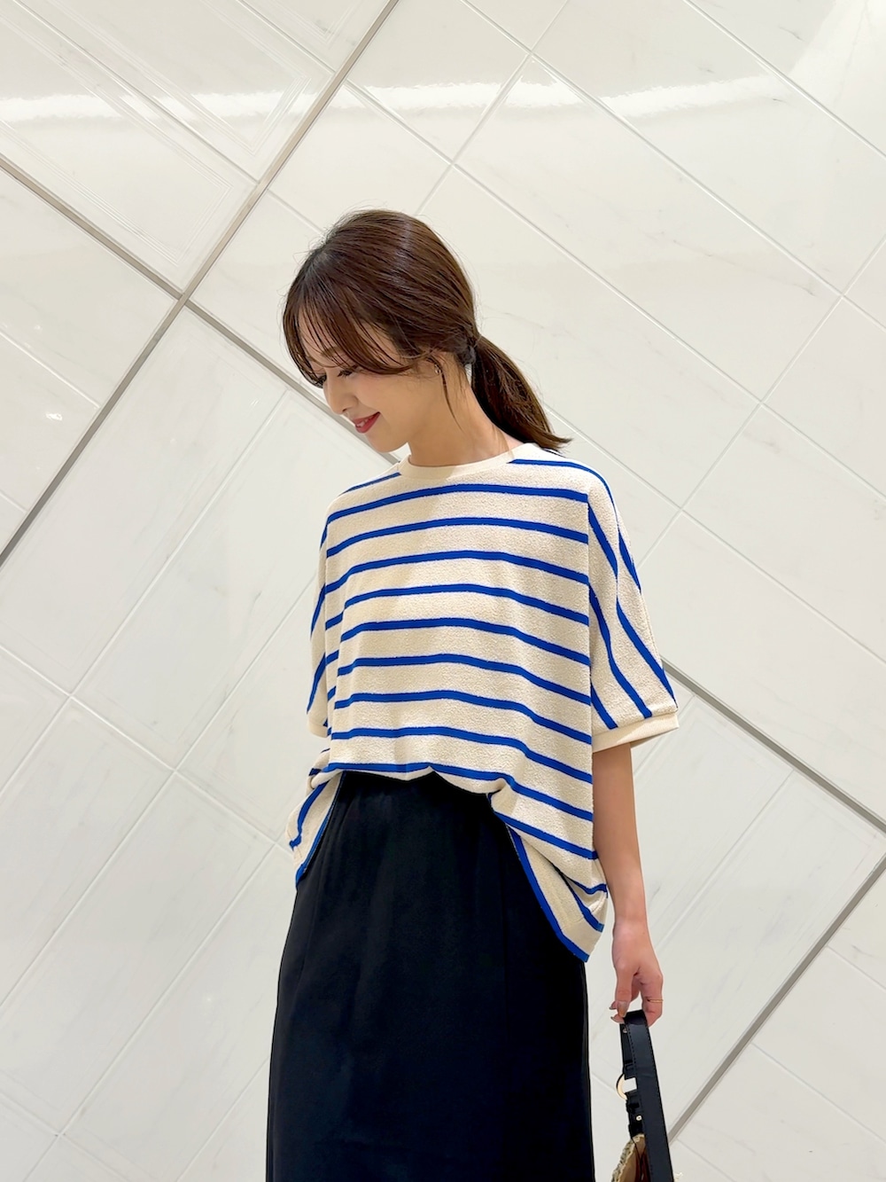 ブラック系のスカート、ベージュ系のトートバッグ、ブルー系のTシャツ/カットソーを着用したレディースの夏コーディネートの4枚目の写真