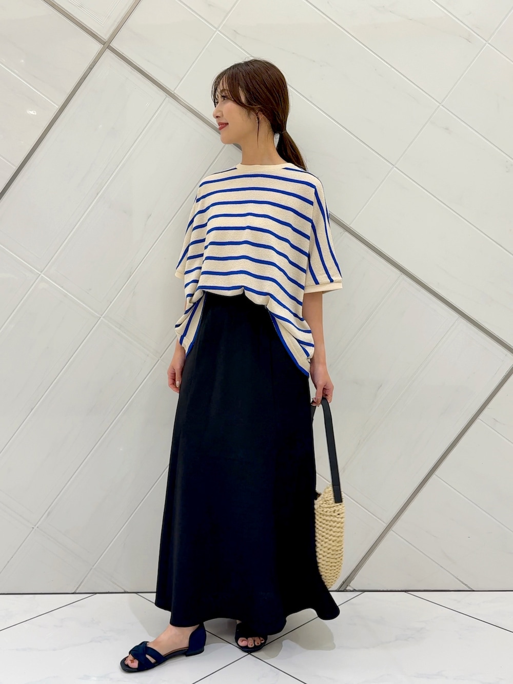 ブラック系のスカート、ベージュ系のトートバッグ、ブルー系のTシャツ/カットソーを着用したレディースの夏コーディネートの2枚目の写真