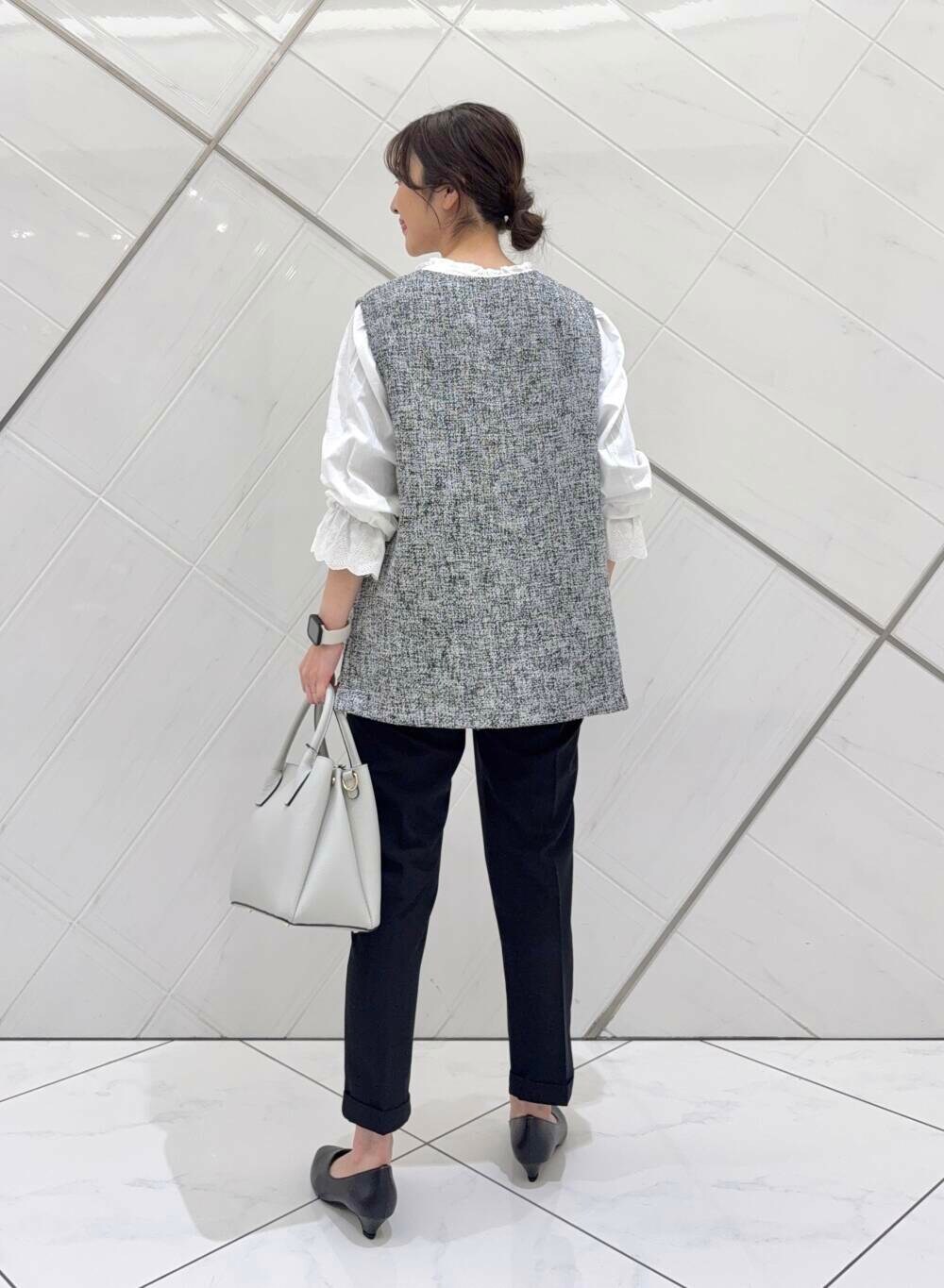 ホワイト系のショルダーバッグ、ホワイト系のシャツ/ブラウス、ブラック系のベストを着用したレディースの冬コーディネートの4枚目の写真