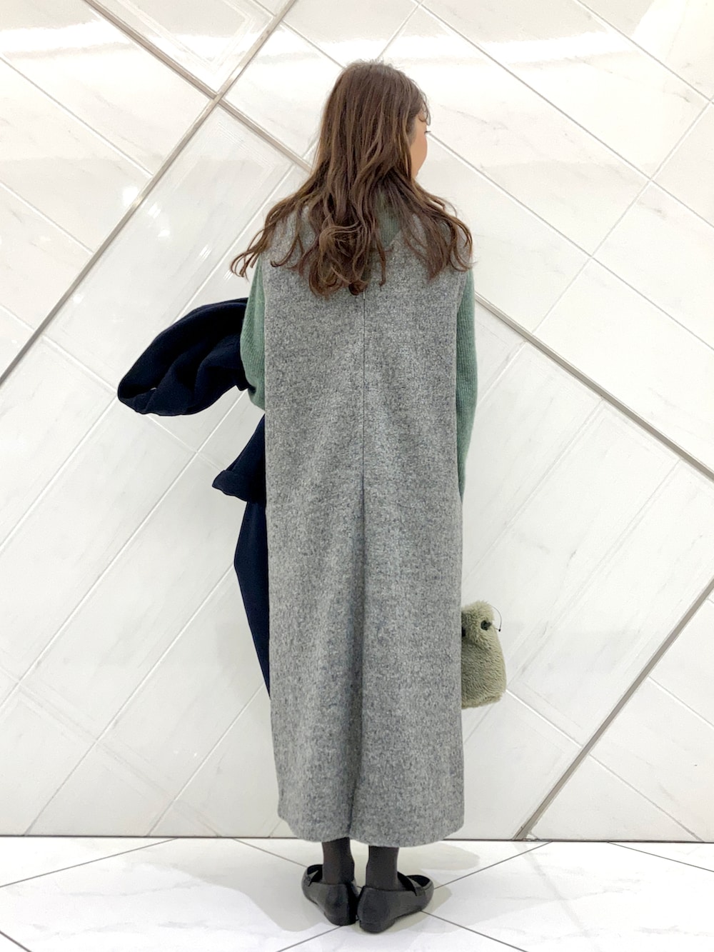 グリーン系のハンドバッグ、ブルー系のチェスターコート、ブラック系のローファーを着用したレディースの冬コーディネートの5枚目の写真