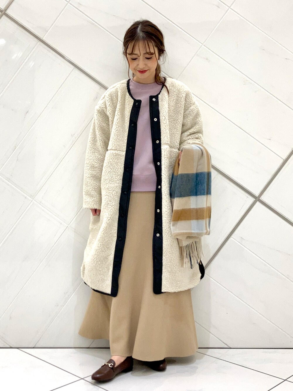 ブラウン系のローファー、ホワイト系のノーカラージャケット、ベージュ系のスカートを着用したレディースの冬コーディネートの3枚目の写真