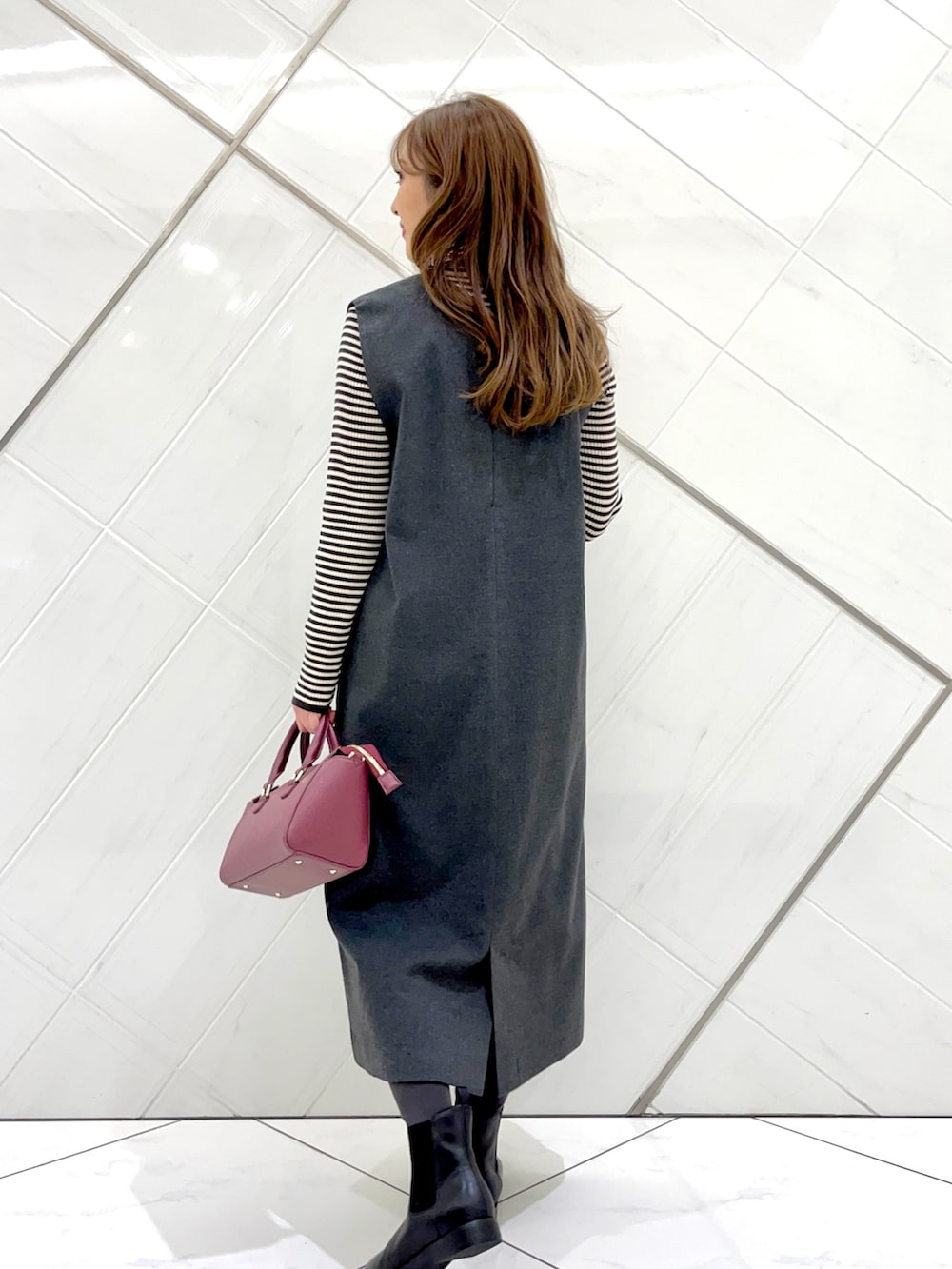 グレー系のステンカラーコート、ホワイト系のニット/セーター、グレー系のワンピースを着用したレディースの冬コーディネートの9枚目の写真