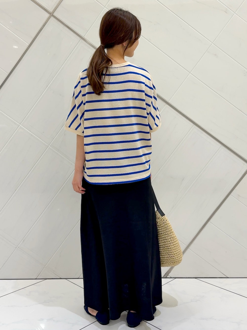 ブラック系のスカート、ベージュ系のトートバッグ、ブルー系のTシャツ/カットソーを着用したレディースの夏コーディネートの7枚目の写真