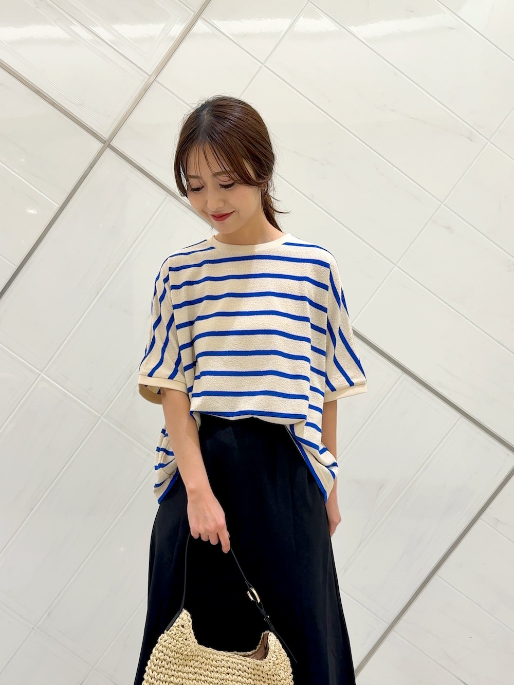ブラック系のスカート、ベージュ系のトートバッグ、ブルー系のTシャツ/カットソーを着用したレディースの夏コーディネートの5枚目の写真