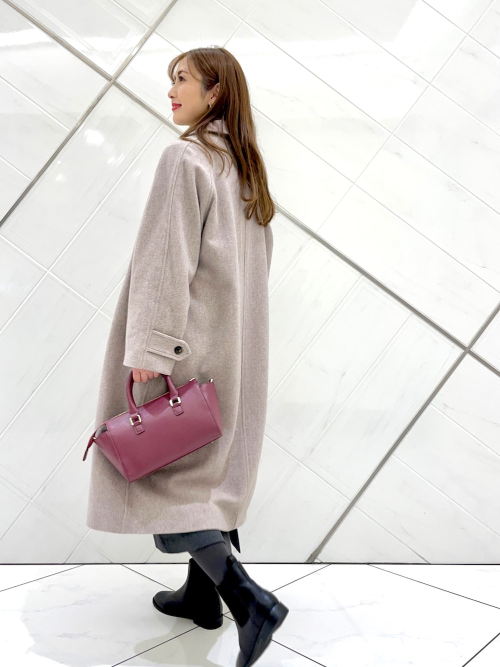 グレー系のステンカラーコート、ホワイト系のニット/セーター、グレー系のワンピースを着用したレディースの冬コーディネートの3枚目の写真