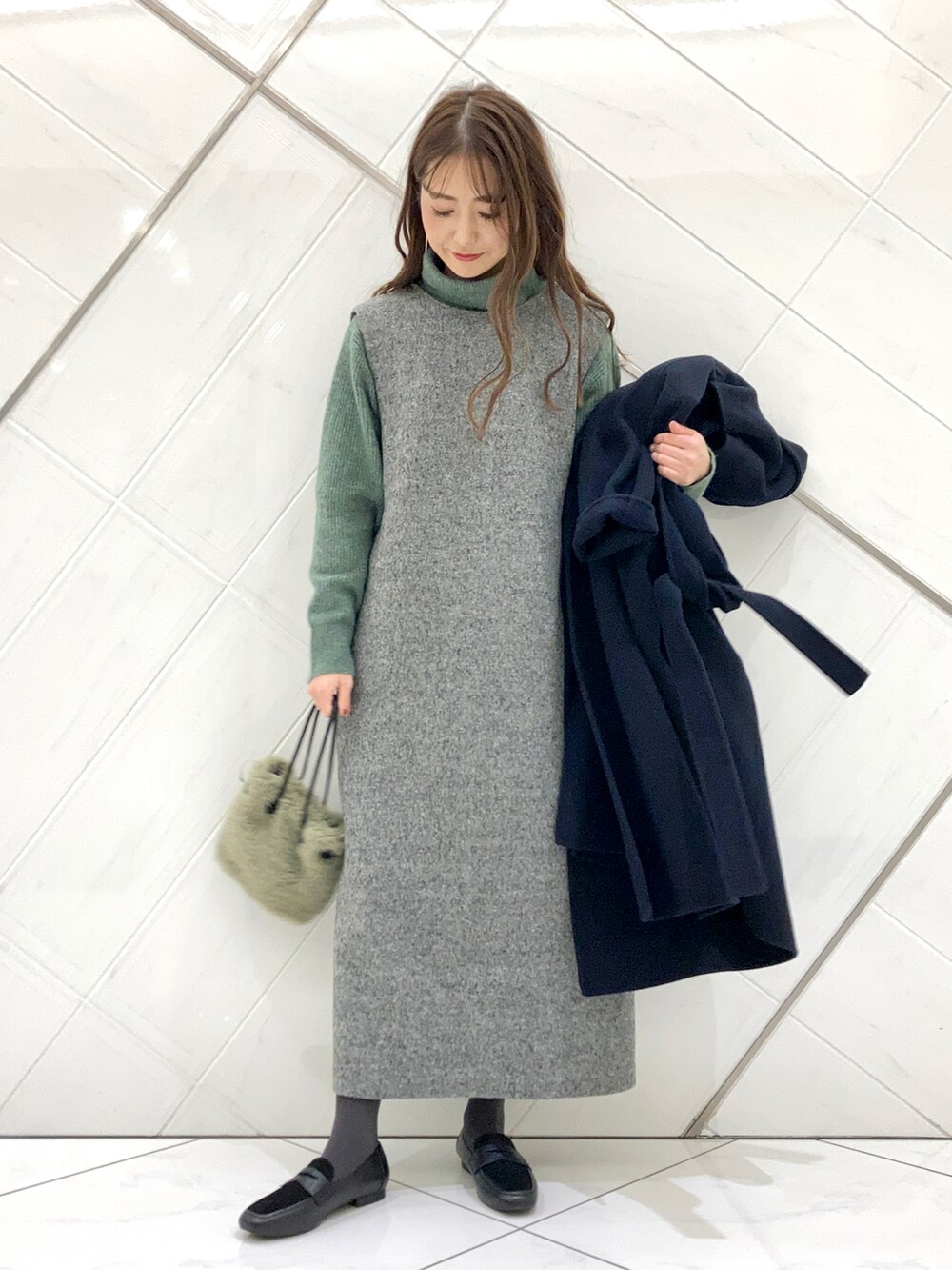 グリーン系のハンドバッグ、ブルー系のチェスターコート、ブラック系のローファーを着用したレディースの冬コーディネートの4枚目の写真