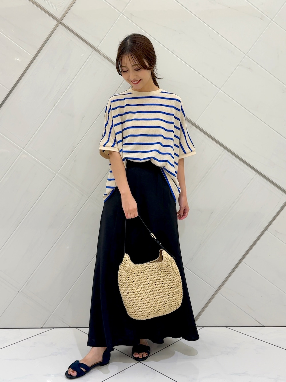 ブラック系のスカート、ベージュ系のトートバッグ、ブルー系のTシャツ/カットソーを着用したレディースの夏コーディネートの3枚目の写真