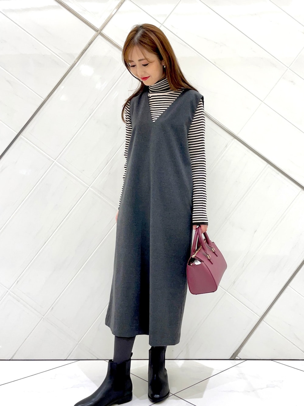 グレー系のステンカラーコート、ホワイト系のニット/セーター、グレー系のワンピースを着用したレディースの冬コーディネートの7枚目の写真