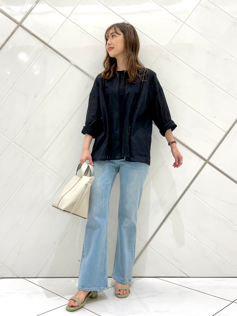 ブルー系のデニムパンツ、グリーン系のサンダル、ブラック系のTシャツ/カットソーを着用したレディースの夏コーディネートの2枚目の写真