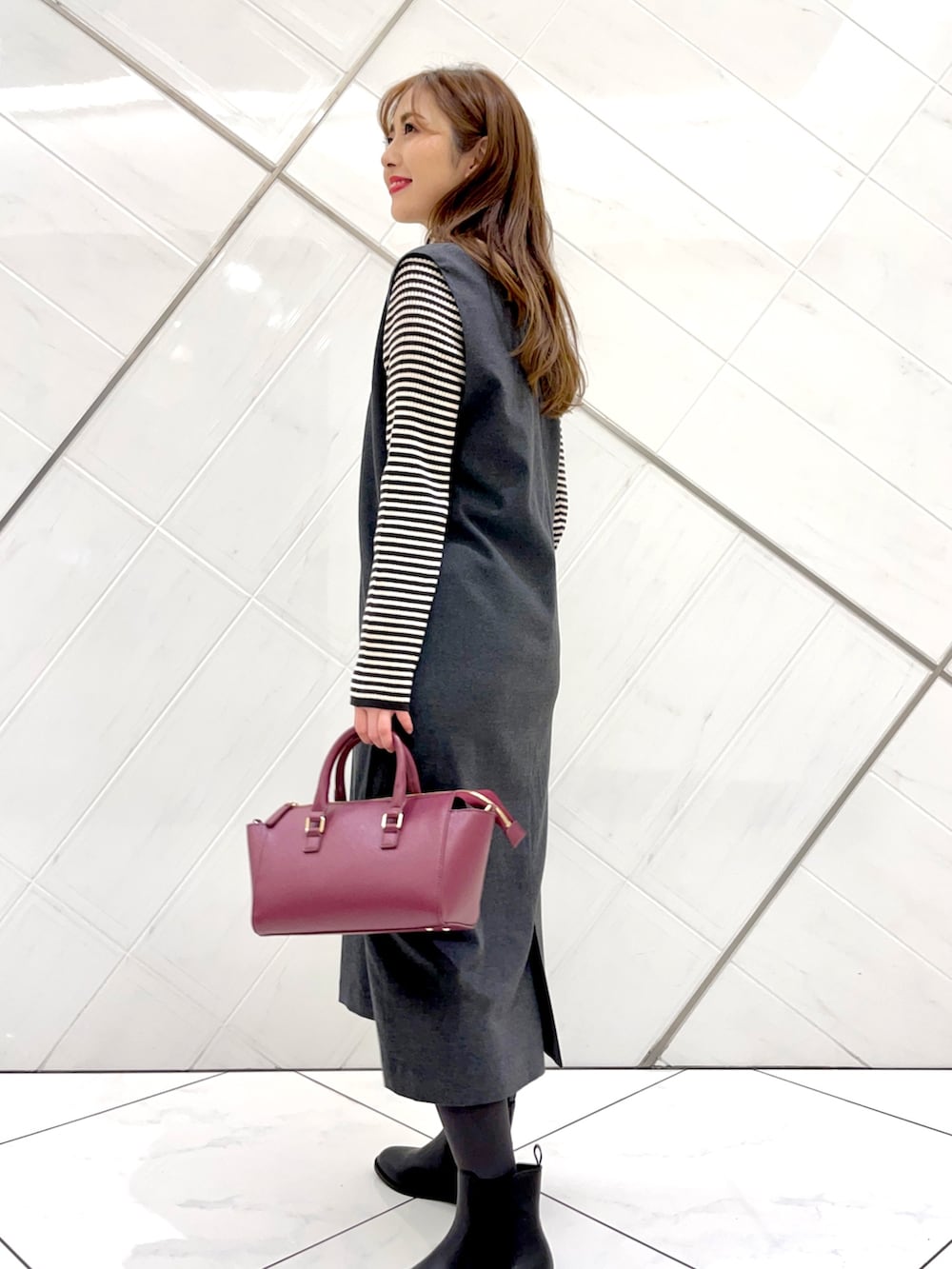 グレー系のステンカラーコート、ホワイト系のニット/セーター、グレー系のワンピースを着用したレディースの冬コーディネートの8枚目の写真