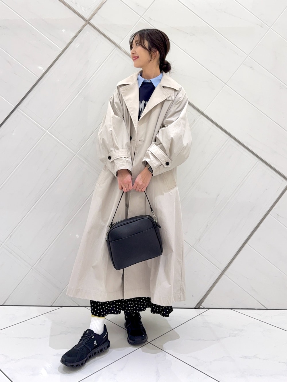 ブルー系のスウェット、ブラック系のスカート、ベージュ系のトレンチコートを着用したレディースの冬コーディネートの2枚目の写真