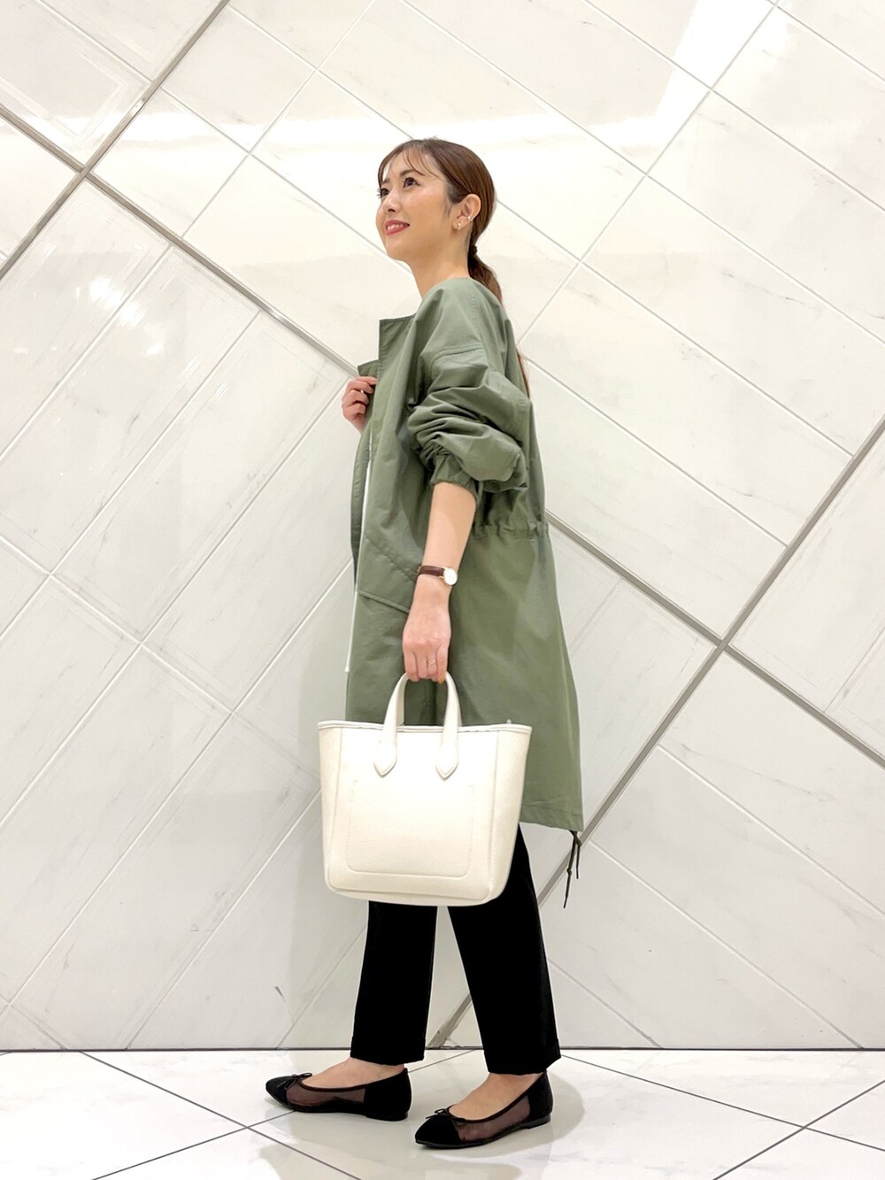グリーン系のモッズコート、ブラック系のその他パンツ、ホワイト系のトートバッグを着用したレディースの春コーディネートの3枚目の写真