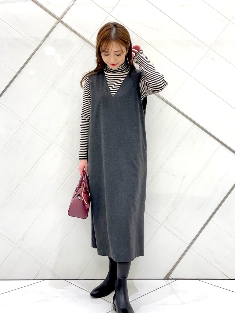 グレー系のステンカラーコート、ホワイト系のニット/セーター、グレー系のワンピースを着用したレディースの冬コーディネートの6枚目の写真