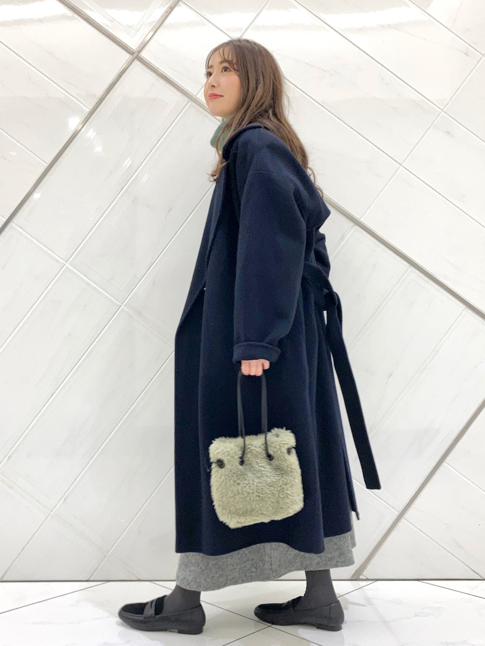 グリーン系のハンドバッグ、ブルー系のチェスターコート、ブラック系のローファーを着用したレディースの冬コーディネートの3枚目の写真