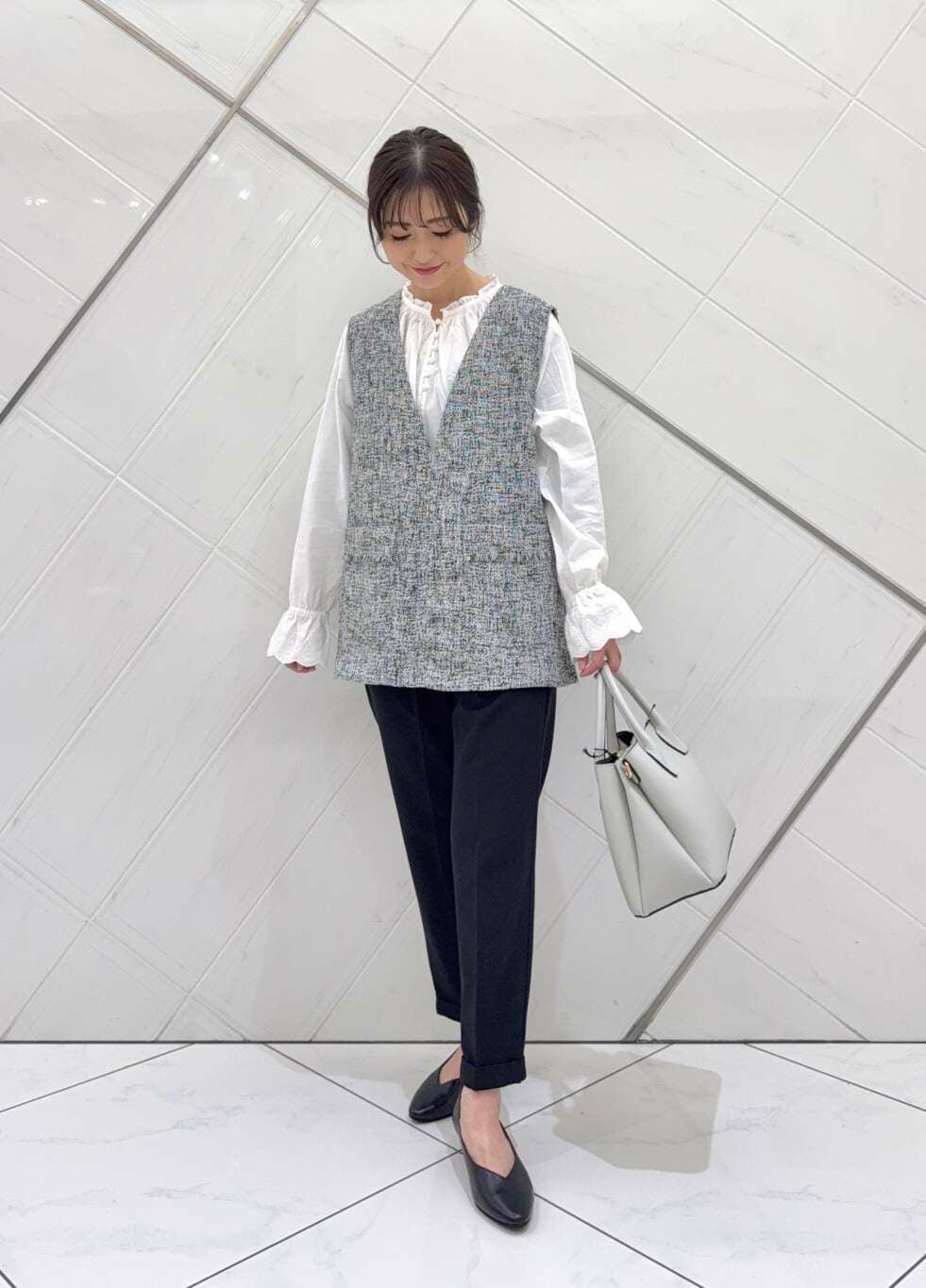 ホワイト系のショルダーバッグ、ホワイト系のシャツ/ブラウス、ブラック系のベストを着用したレディースの冬コーディネートの3枚目の写真