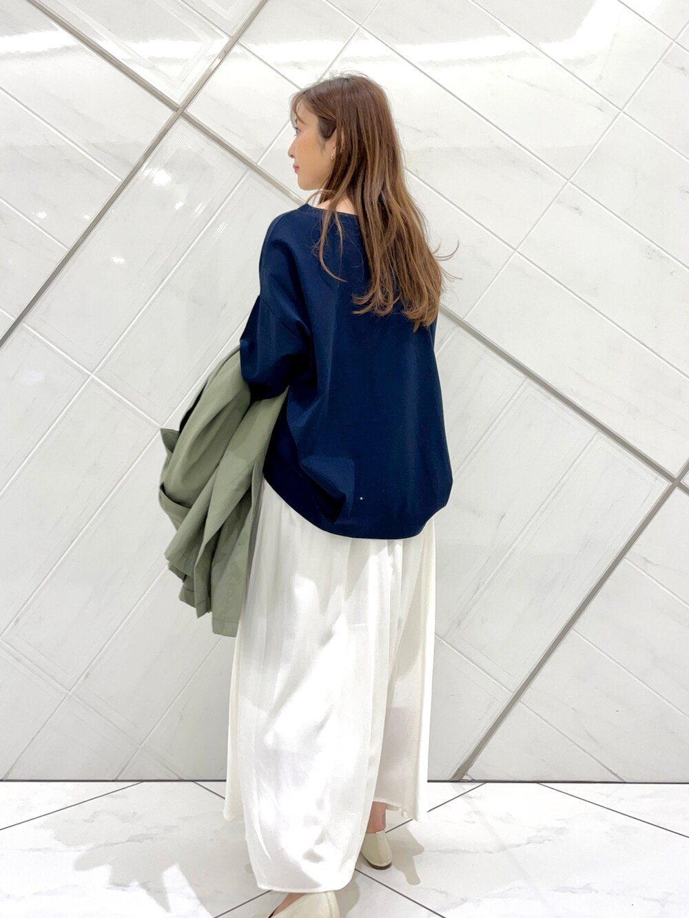 グリーン系のポンチョ、ホワイト系のスカート、ブルー系のTシャツ/カットソーを着用したレディースの春コーディネートの6枚目の写真