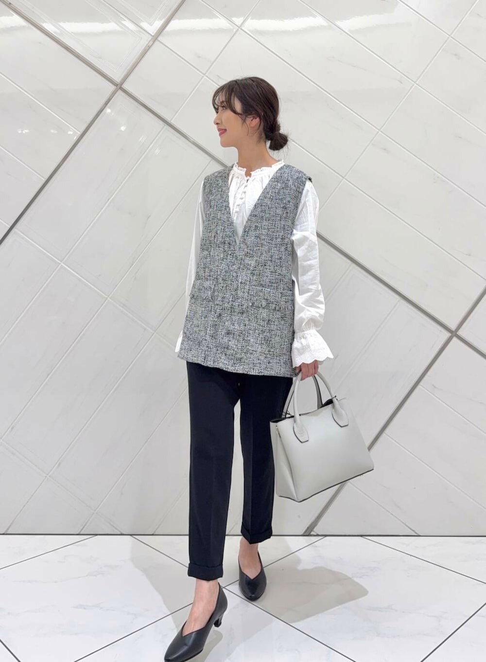 ホワイト系のショルダーバッグ、ホワイト系のシャツ/ブラウス、ブラック系のベストを着用したレディースの冬コーディネートの2枚目の写真