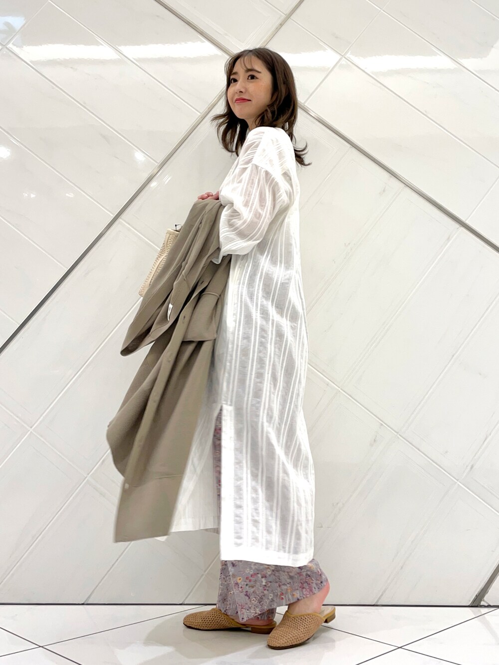 ベージュ系のニット/セーター、グレー系のその他パンツ、ホワイト系のワンピースを着用したレディースの春コーディネートの5枚目の写真