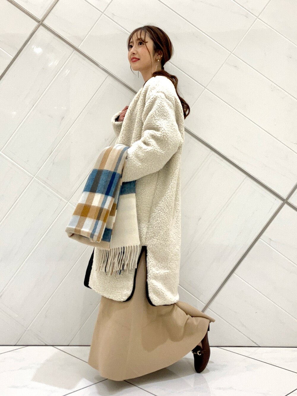 ブラウン系のローファー、ホワイト系のノーカラージャケット、ベージュ系のスカートを着用したレディースの冬コーディネートの2枚目の写真
