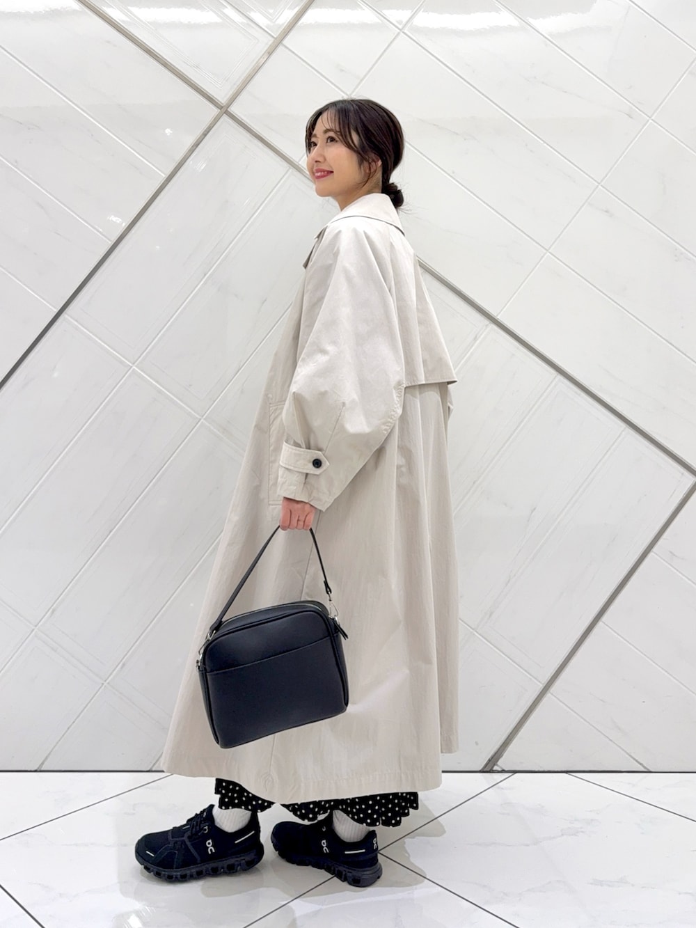 ブルー系のスウェット、ブラック系のスカート、ベージュ系のトレンチコートを着用したレディースの冬コーディネートの4枚目の写真