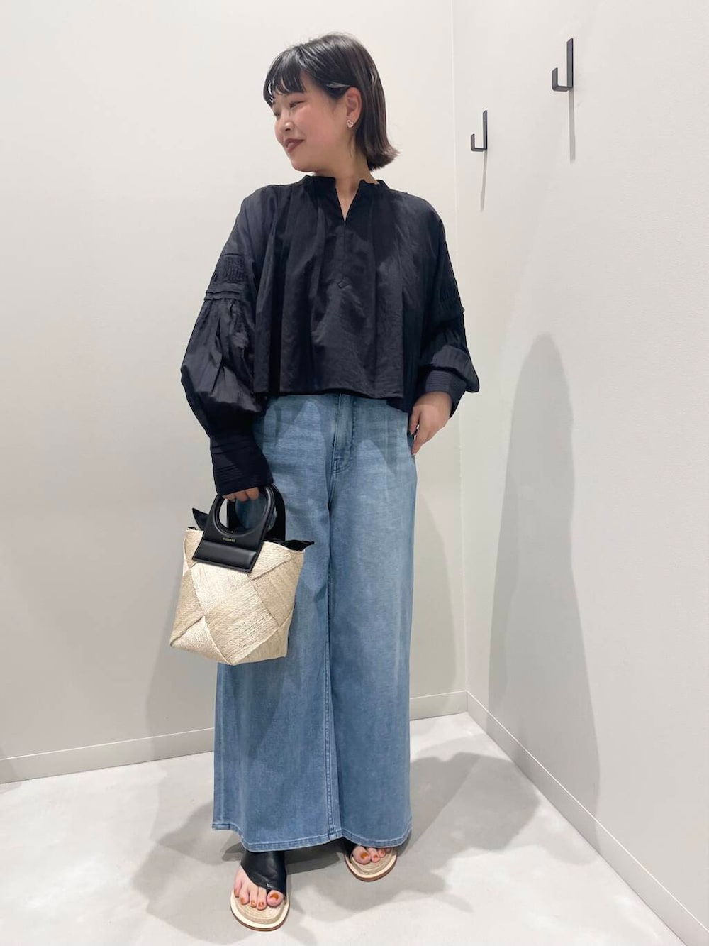 ベージュ系のショルダーバッグ、ブラック系のシャツ/ブラウス、ブルー系のデニムパンツを着用したレディースの春コーディネートの2枚目の写真