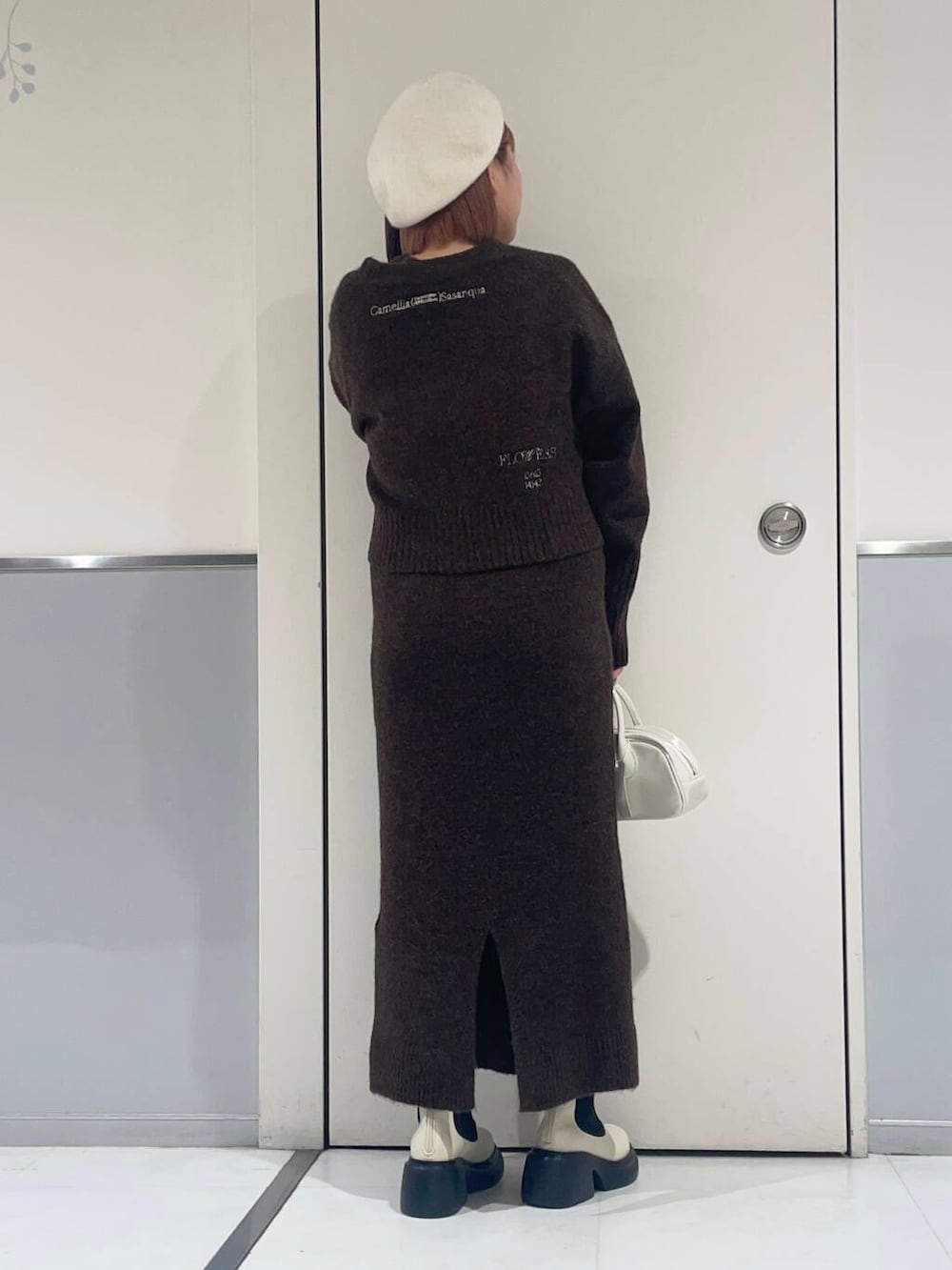 ホワイト系のブーツ、ホワイト系のボストンバッグ、ブラウン系のワンピースを着用したレディースの冬コーディネートの2枚目の写真