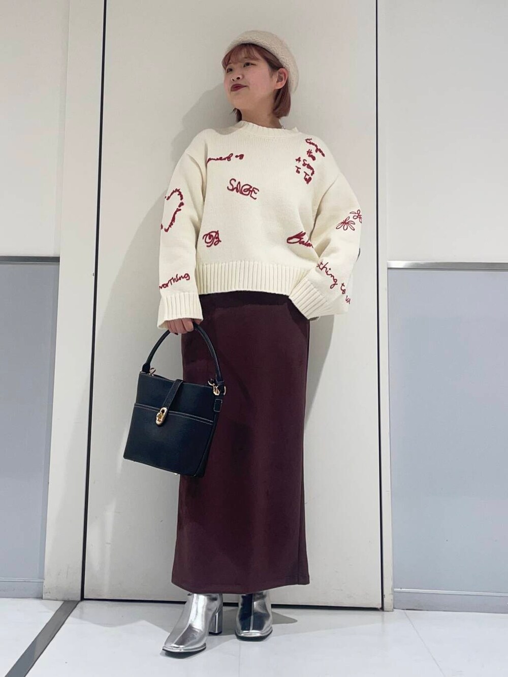 ホワイト系のニット/セーター、ブラック系のハンドバッグ、シルバー系のブーツを着用したレディースの冬コーディネートの2枚目の写真