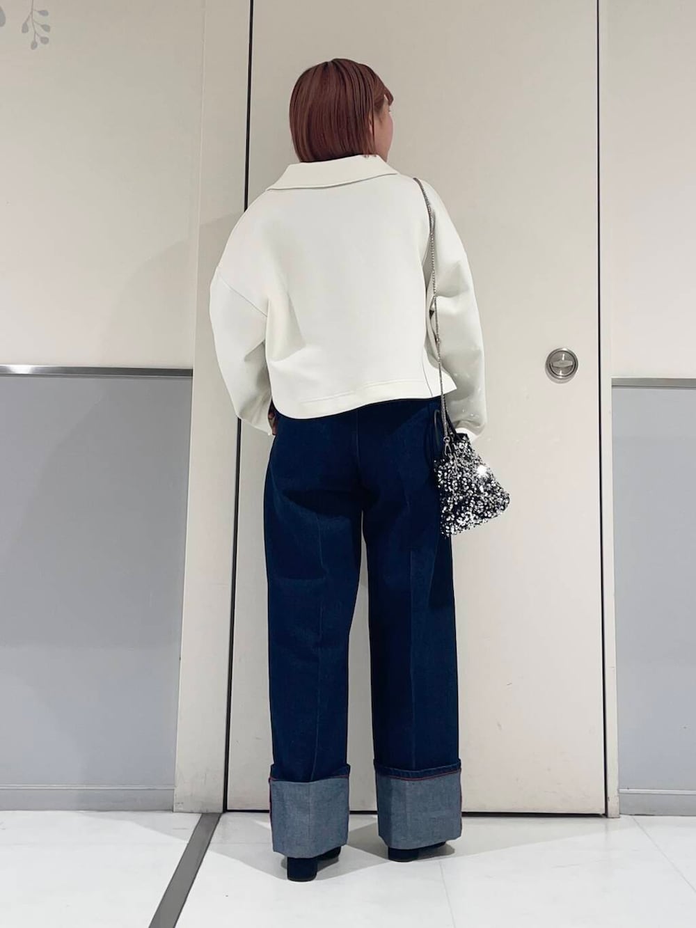 シルバー系のショルダーバッグ、レッド系のニット/セーター、ブラック系のブーツを着用したレディースの冬コーディネートの2枚目の写真