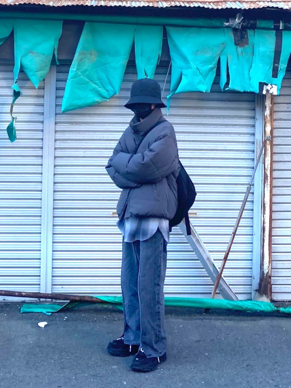 グレー系のダウンジャケット/コート、グレー系のデニムパンツ、ブラック系のスニーカーを着用したメンズの春コーディネートの2枚目の写真